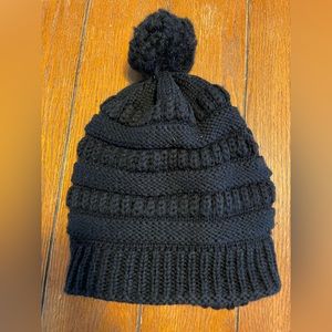 Black slouchy acrylic beanie lined with a Pom